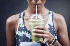 特写镜头活跃的女人喝健康的绿色排毒奶昔锻炼在户外女运动员喝着新鲜的水果汁稻草塑料杯净化提供能源培训有益健康的喝维生素营养物质