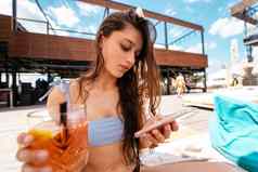 年轻的女人手机聊天在线游泳池