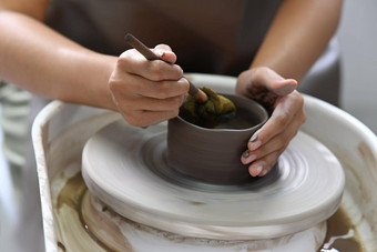 关闭视图年轻的女人穿围裙创建手工制作的陶瓷碗陶器车间