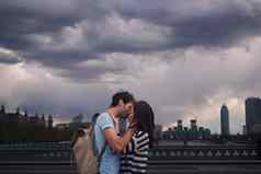 中间风暴发现年轻的夫妇接吻桥俯瞰城市伦敦多云的一天