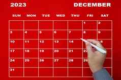 12月日历手持有黑色的笔红色的背景