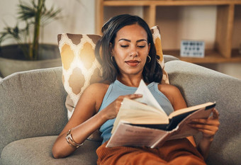 混合比赛女人阅读书生活房间首页美丽的拉美裔说谎休息室沙发享受放松女人穿眼镜读小说故事周末