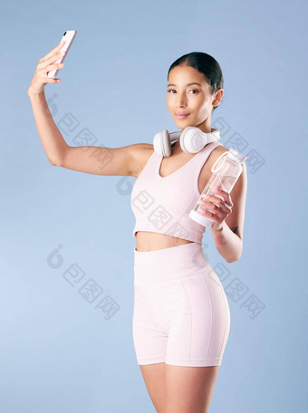 混合比赛健身女人摆姿势电话工作室蓝色的背景年轻的拉美裔女运动员采取自拍图片智能手机跟踪个人健身增长