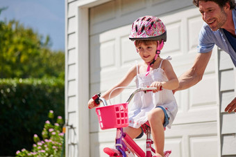 教学独立的技能年轻的父亲教学女儿骑自行车