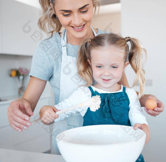 妈妈。女儿烘焙首页快乐妈妈。孩子成键烹饪女人帮助女儿使面糊年轻的妈妈。持有蛋烘焙女孩