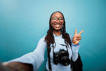 兴奋快乐的摄影爱好者采取自拍照片站蓝色的背景