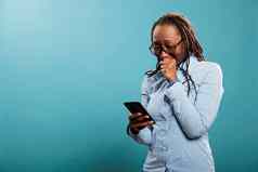 心烦意乱年轻的女人哭阅读悲剧新闻智能手机设备站蓝色的背景