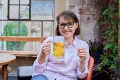 微笑中间岁的女玻璃光啤酒相机德国酒吧