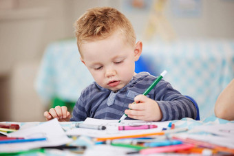 可爱的高加索人男孩画图片书坐着表格着色学前教育幼儿园年轻的孩子色彩鲜艳的铅笔画图片教室