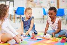 集团多样化的可爱的女孩坐着交叉腿地板上学前教育茶聚会，派对可爱的孩子们玩成键学校非洲美国孩子朋友