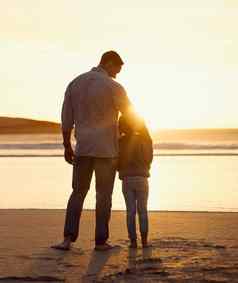 后视图拍摄父亲女儿支出时间海滩日落爱的父亲拥抱女孩站海