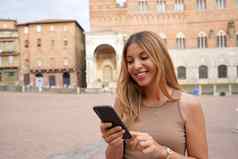 肖像快乐年轻的女人滚动信息手指智能手机历史城市意大利