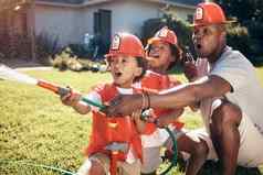 男孩消防员服装非洲美国父亲玩孩子们男孩玩花园男孩喷涂水水龙软管兴奋兄弟玩