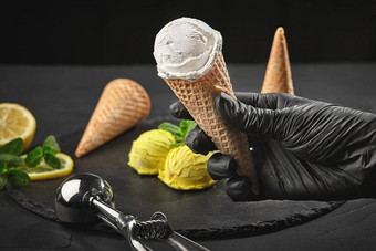 手黑暗手套持有华夫格锥奶油冰奶油背景柠檬冰沙装饰薄荷