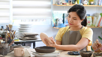 年轻的女人使陶瓷能陶器艺术类车间在室内活动工艺品爱好概念