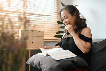 和平中间岁的女人吃饼干阅读书沙发上首页休闲活动积极的情绪概念