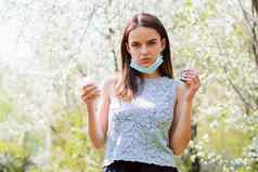概念春天疾病年轻的女医疗面具持有餐巾喷雾过敏发热冷运行鼻子盛开的花园