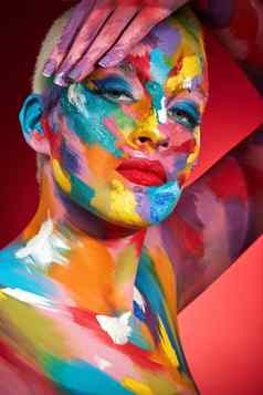 行生活鲜艳工作室拍摄年轻的女人摆姿势五颜六色的油漆脸