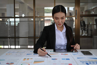 专业女商人分析市场营销研究结果销售统计数据数据办公室桌子上