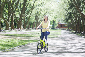 活跃的退休女人游乐设施自行车夏天公园高级头发花白的退休女人走