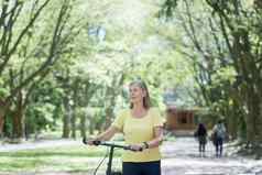 退休女人休息公园头发花白的波斯女人走自行车夏天一天