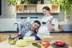 年轻的家庭怀孕了女人男人。准备健康的美味的食物