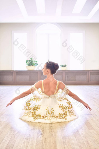 回来视图美丽的芭蕾舞女演员奶油衣服坐着变暖手木地板上芭蕾舞工作室