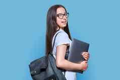 十几岁的女学生背包移动PC蓝色的颜色背景