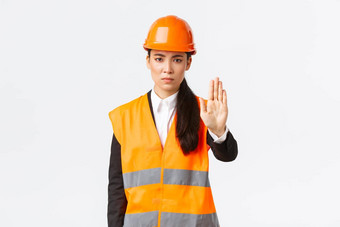 严肃的表情失望亚洲女架构师建设经理工作区域穿安全头盔显示停止手势禁止行动禁止非法侵入白色背景