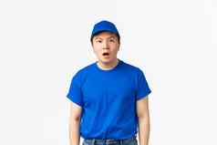 肖像震惊了惊讶亚洲交付的家伙蓝色的统一的帽t恤反应惊人的下降下巴站在相机说不出话来白色背景