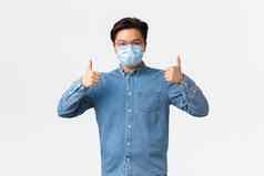 科维德防止病毒社会距离工作场所概念自信亚洲男人。衬衫医疗面具显示竖起大拇指确保安全员工冠状病毒