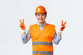 建筑部门工业工人概念可爱的快乐的亚洲建设经理工程师头盔手套显示和平标志微笑牙齿牙套白色背景