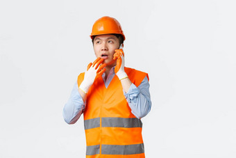 建筑部门工业工人概念深思熟虑的亚洲工程师工作建设区域穿头盔反光衣服回答问题移动电话思考