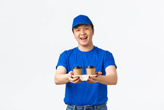在线订单外卖员工概念友好的微笑亚洲交付男人。蓝色的快递统一的将杯咖啡客户快乐的表达式站白色背景
