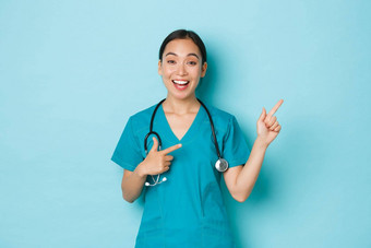 科维德社会距离冠状病毒流感大流行概念快乐友善的微笑亚洲女护士医生实习生实习医生风云指出手指上角落里显示广告