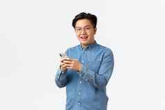 微笑娱乐亚洲男人。牙套穿眼镜消息传递看视频互联网移动电话应用程序相机很高兴站白色背景