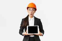 深刻的印象亚洲女建设工程师女商人安全头盔西装显示图表介绍双字母组合digial平板电脑屏幕站惊讶白色背景