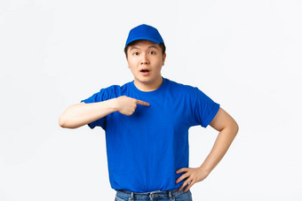 惊讶震惊了亚洲快递交付的家伙蓝色的统一的帽t恤困惑指出担心命名站白色背景