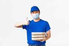 非接触式交付科维德航运防止病毒概念微笑亚洲快递蓝色的统一的医疗面具手套提供安全快交付显示竖起大拇指将披萨盒子