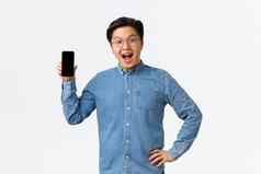 快乐逗乐英俊的亚洲的家伙牙套眼镜反应神奇的新闻显示移动电话屏幕介绍应用程序商店站白色背景惊讶