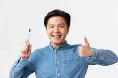 口腔正畸学牙科护理卫生概念特写镜头满意亚洲男人。显示竖起大拇指推荐牙刷牙巴斯特牙齿牙套微笑很高兴