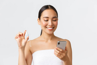 美个人亲密的护理移动应用程序概念微笑漂亮的亚洲女孩期穿毛巾月经周期跟踪器应用程序智能手机持有止血栓