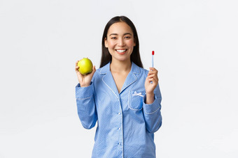 早....活跃的健康的生活方式首页概念微笑美丽的亚洲女孩显示牙刷绿色苹果完美的白色牙齿给建议口卫生白色背景