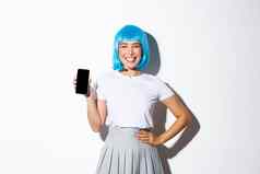 肖像可爱的亚洲女孩穿着动漫字符蓝色的假发微笑快乐显示智能手机屏幕站白色背景