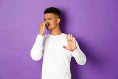 图像非裔美国人的家伙拒绝可怕的气味关闭鼻子臭显示停止手势下降提供站紫色的背景