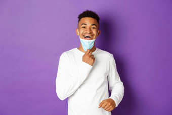 概念科维德流感大流行社会距离快乐非裔美国人男人。除去医疗面具呼吸自由站紫色的背景