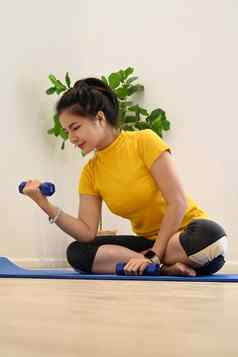 活跃的年轻的女人锻炼例程锻炼哑铃首页健康的生活方式体育运动概念