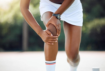 不会竞争特写镜头拍摄运动年轻的女人经历<strong>膝盖疼痛</strong>玩网球在户外