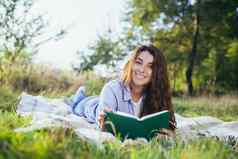 美丽的年轻的学生女孩读取书研究说谎草自然