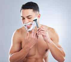 光滑的刮胡子工作室拍摄英俊的年轻的男人。剃须灰色背景